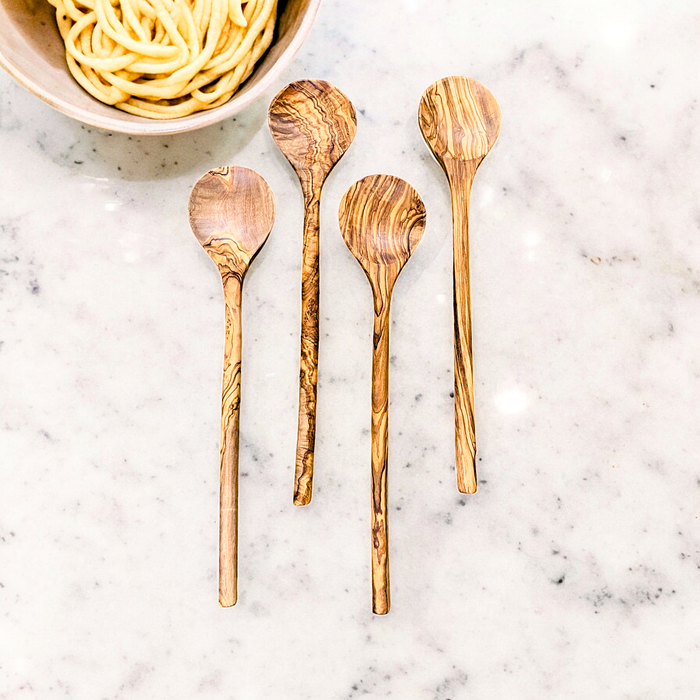 Handcrafted long olive wood stirring spoons with round heads, suitable for non-stick surfaces and stainless steel, placed on a marble countertop.