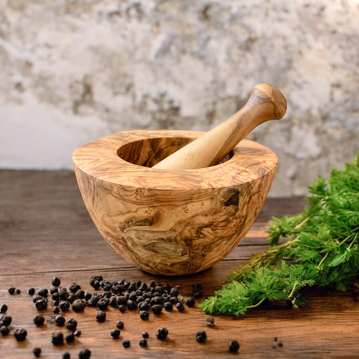 Handcrafted olive wood mortar and pestle for grinding spices, a timeless kitchen essential on a rustic wooden table.