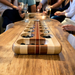 Classic mancala board game made from beautiful exotic woods on a wooden table surrounded  by friends at a party.