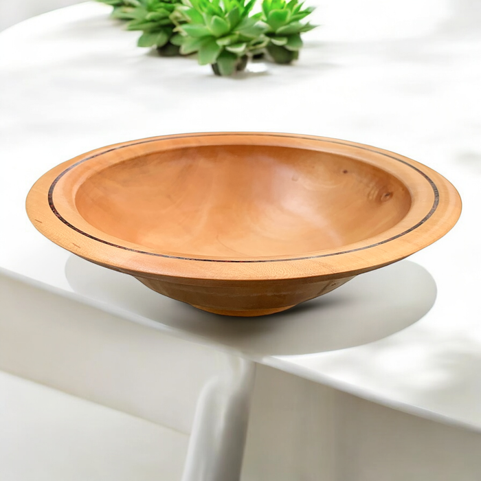 Maple wood dish with dark inlay accent and smooth finish, crafted by Dennis Belcher, displayed on a white table with greenery in the background.