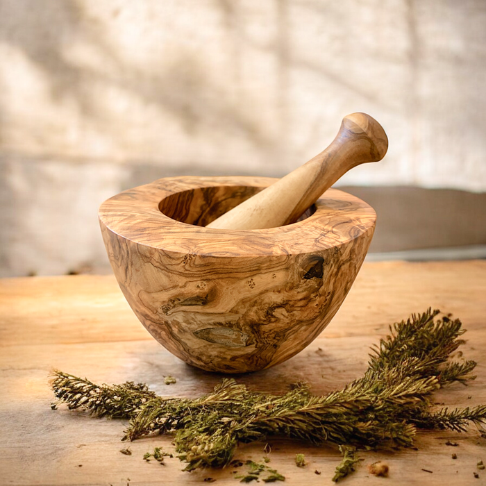 Handcrafted olive wood mortar and pestle with rustic herbs, perfect for traditional grinding in any kitchen.