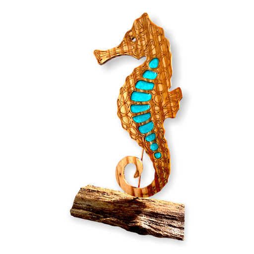 This single wooden seahorse with aqua blue epoxy accents is displayed on a rustic pine wood base and basks in the sunlight.. 